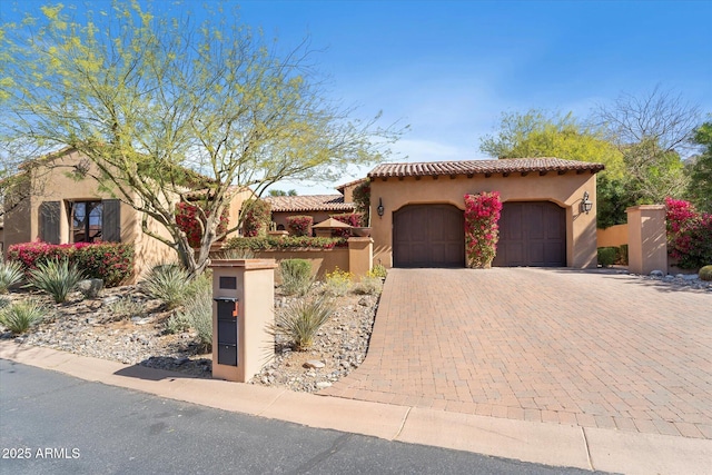 mediterranean / spanish home featuring a garage, a tile roof, fence, decorative driveway, and stucco siding