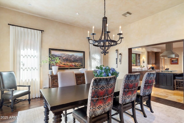 dining room featuring a chandelier, a wealth of natural light, visible vents, and wood finished floors