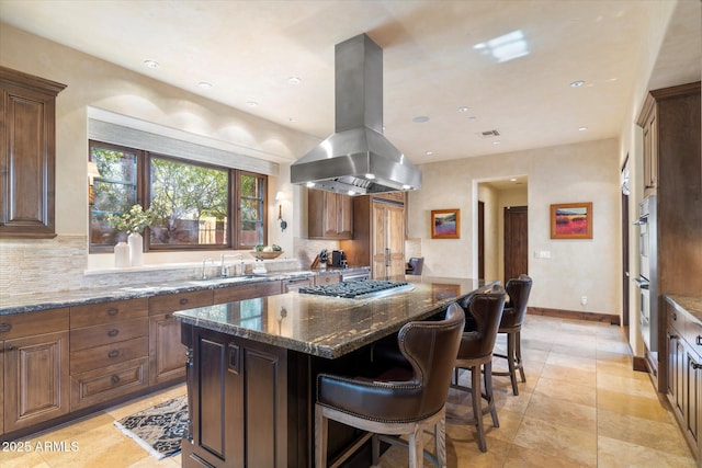 kitchen featuring decorative backsplash, a center island, island exhaust hood, stainless steel appliances, and a sink