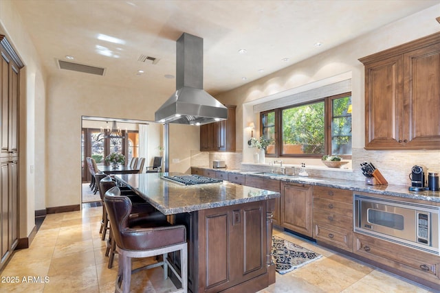 kitchen featuring appliances with stainless steel finishes, island exhaust hood, visible vents, and tasteful backsplash