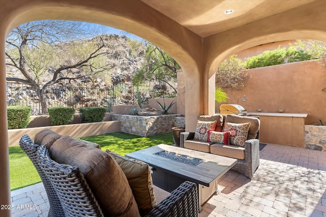 view of patio / terrace featuring fence and an outdoor living space with a fire pit