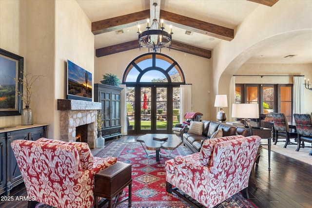 living room featuring arched walkways, high vaulted ceiling, a notable chandelier, a premium fireplace, and beam ceiling