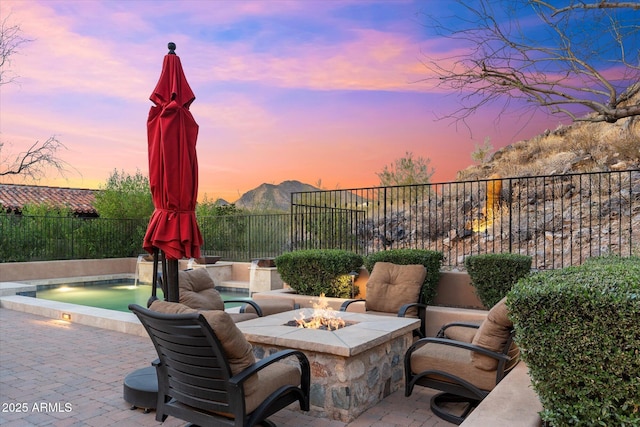 patio terrace at dusk with a fenced backyard and a fire pit