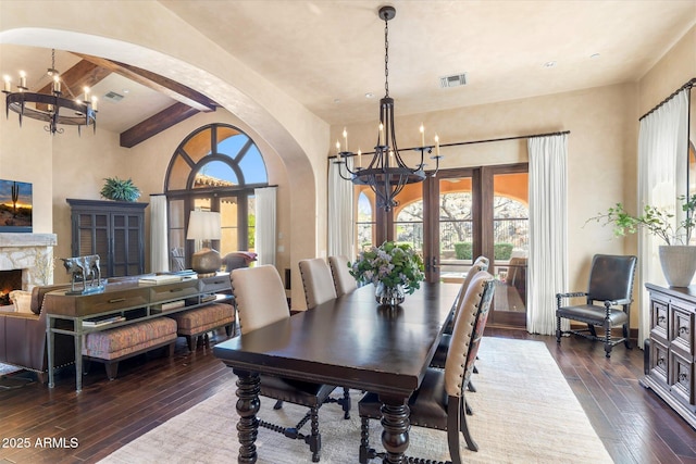 dining room featuring arched walkways, dark wood-type flooring, visible vents, and an inviting chandelier