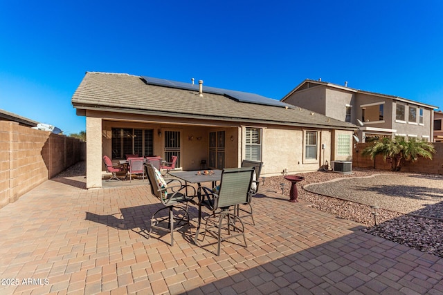 rear view of property with solar panels, cooling unit, and a patio area