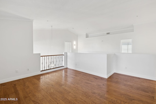 spare room featuring hardwood / wood-style flooring, ornamental molding, and vaulted ceiling