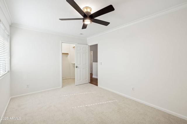 unfurnished bedroom featuring a walk in closet, light colored carpet, ceiling fan, crown molding, and a closet