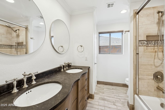 full bathroom with ornamental molding, vanity, bath / shower combo with glass door, and toilet