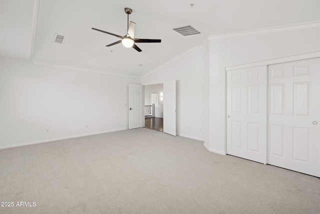 unfurnished bedroom with lofted ceiling, ornamental molding, light colored carpet, ceiling fan, and a closet