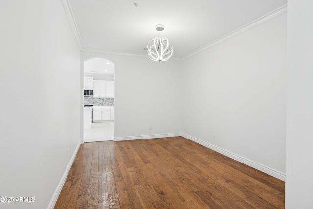 unfurnished room with wood-type flooring, ornamental molding, and a chandelier