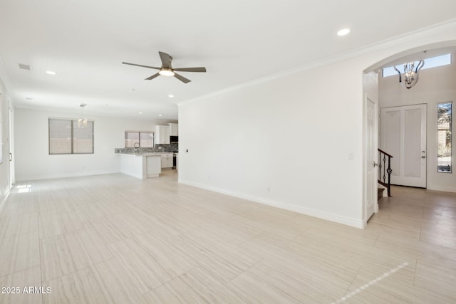 unfurnished living room featuring sink, ceiling fan with notable chandelier, and ornamental molding