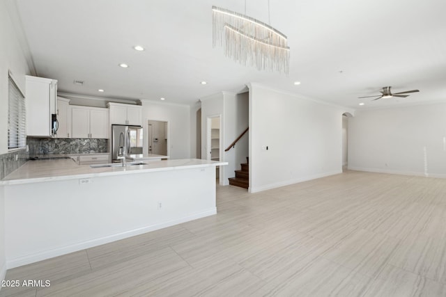 kitchen featuring sink, tasteful backsplash, hanging light fixtures, appliances with stainless steel finishes, and white cabinets