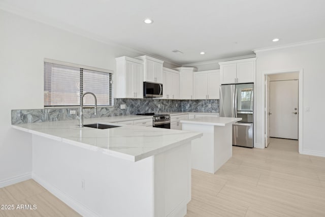 kitchen featuring sink, appliances with stainless steel finishes, kitchen peninsula, decorative backsplash, and white cabinets