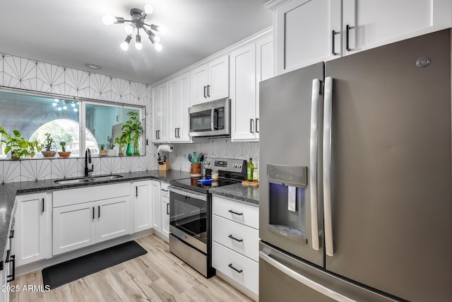 kitchen featuring a sink, white cabinets, appliances with stainless steel finishes, dark stone counters, and tasteful backsplash