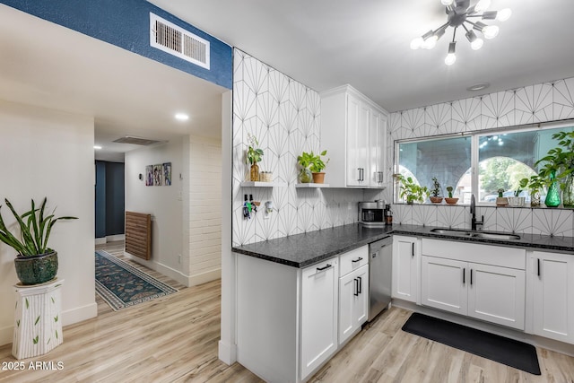 kitchen with visible vents, stainless steel dishwasher, light wood-style floors, white cabinetry, and a sink