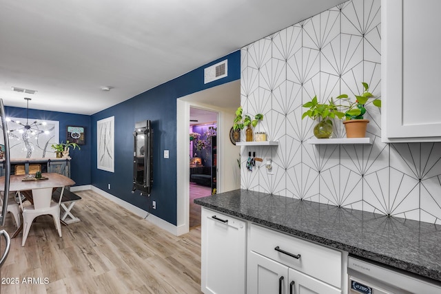 kitchen featuring visible vents, dark stone counters, dishwasher, light wood-type flooring, and white cabinetry