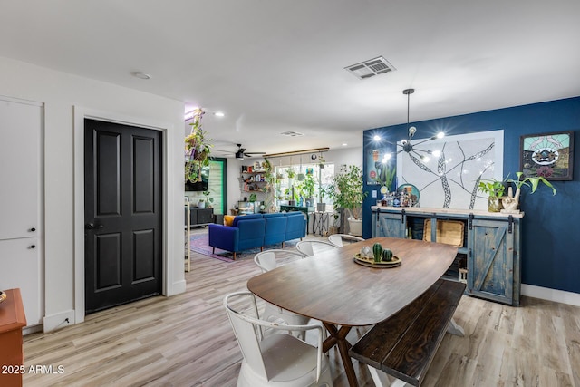 dining space featuring light wood-style flooring, visible vents, baseboards, and ceiling fan with notable chandelier