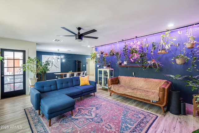 living room with ceiling fan with notable chandelier, wood finished floors, and visible vents