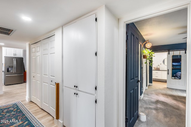 hall with a barn door, light wood-type flooring, and visible vents