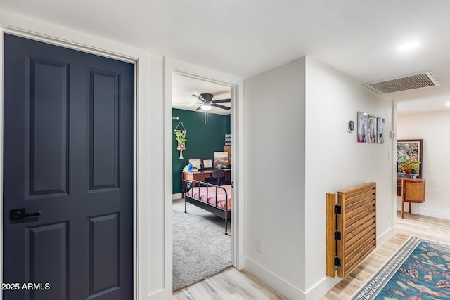 corridor featuring visible vents, light wood-style flooring, and baseboards