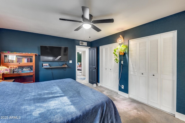 bedroom with ceiling fan, carpet flooring, visible vents, baseboards, and multiple closets