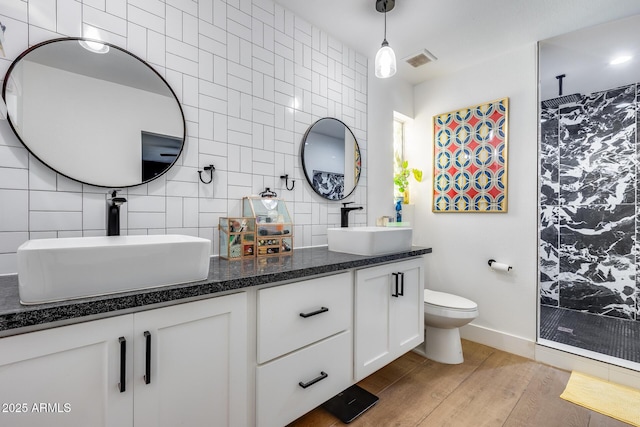 bathroom featuring a tile shower, wood finished floors, and a sink