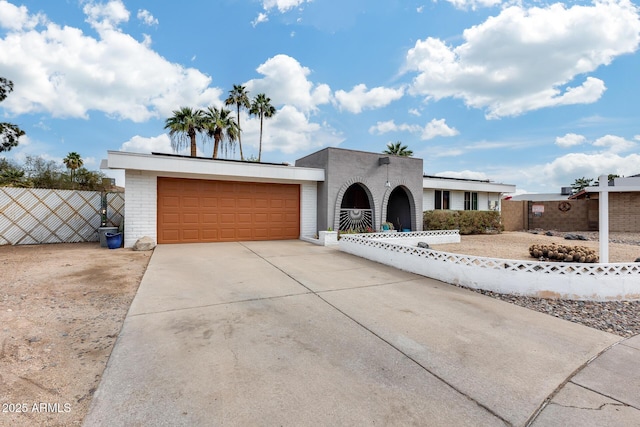 view of front of house featuring driveway, a garage, fence, and brick siding