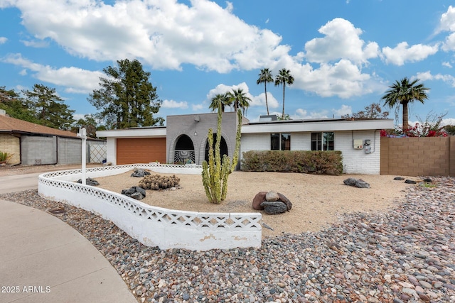 view of front facade featuring concrete driveway, brick siding, fence, and an attached garage