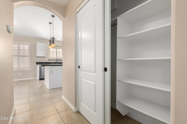 hall featuring light tile patterned flooring and sink