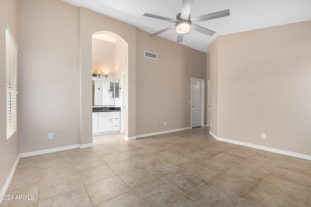 empty room featuring light tile patterned flooring, ceiling fan, and a towering ceiling