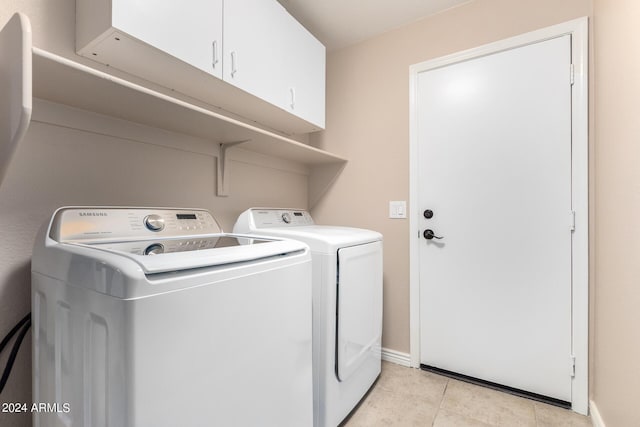 washroom featuring cabinets, washing machine and clothes dryer, and light tile patterned flooring