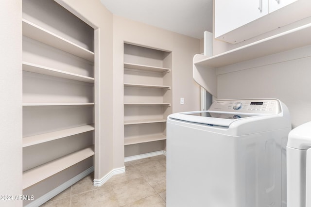 clothes washing area featuring washer / dryer, cabinets, and light tile patterned flooring