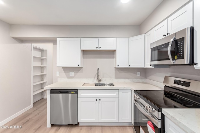 kitchen with stainless steel appliances, light stone countertops, sink, and white cabinets