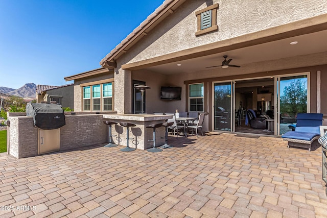 view of patio featuring a mountain view, an outdoor kitchen, and a ceiling fan