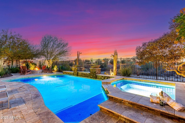 pool at dusk with an in ground hot tub and a patio