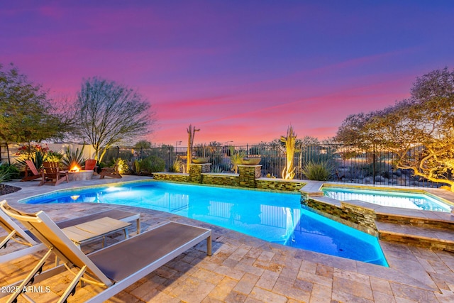 pool at dusk featuring an in ground hot tub and a patio area