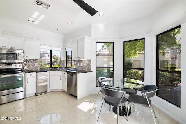 kitchen featuring appliances with stainless steel finishes, backsplash, and white cabinetry