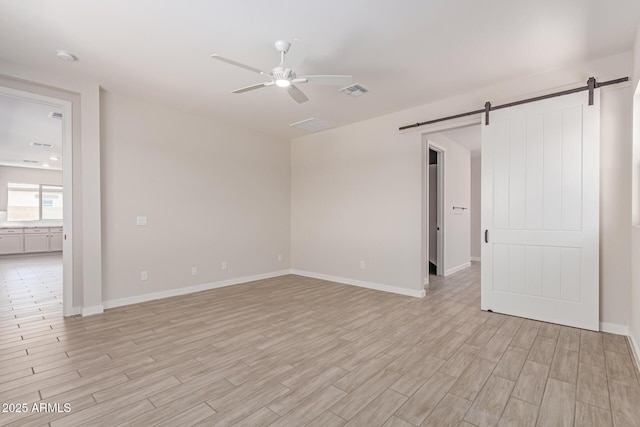 8553 N 175th Ln, Waddell, AZ 85355 - empty room with a barn door, ceiling fan, light wood-style flooring, and baseboards