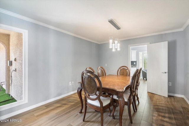 dining space with crown molding, a notable chandelier, and wood-type flooring