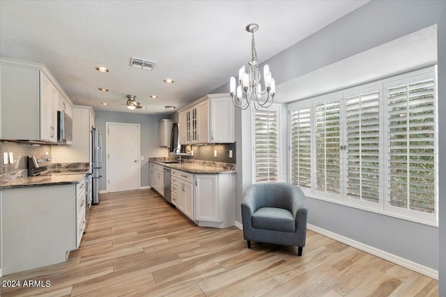 kitchen with light hardwood / wood-style floors, white cabinets, stainless steel appliances, and a wealth of natural light