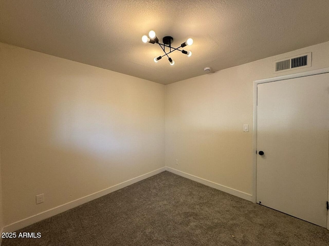 spare room featuring dark colored carpet and a textured ceiling