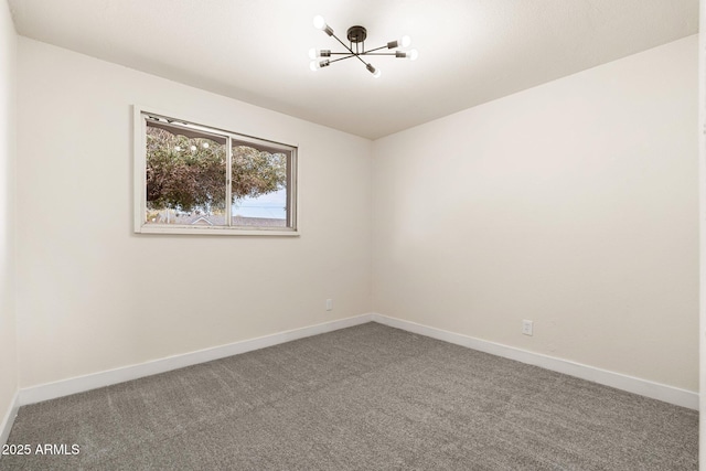 spare room featuring carpet flooring and a notable chandelier