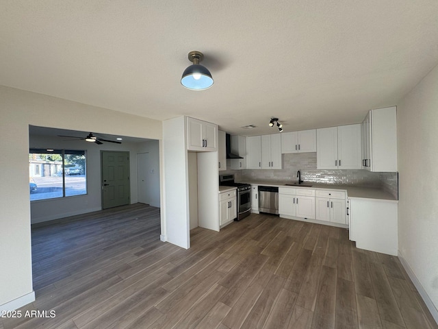 kitchen featuring wall chimney exhaust hood, sink, tasteful backsplash, stainless steel appliances, and white cabinets