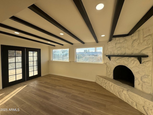 unfurnished living room with french doors, beamed ceiling, a fireplace, and hardwood / wood-style flooring