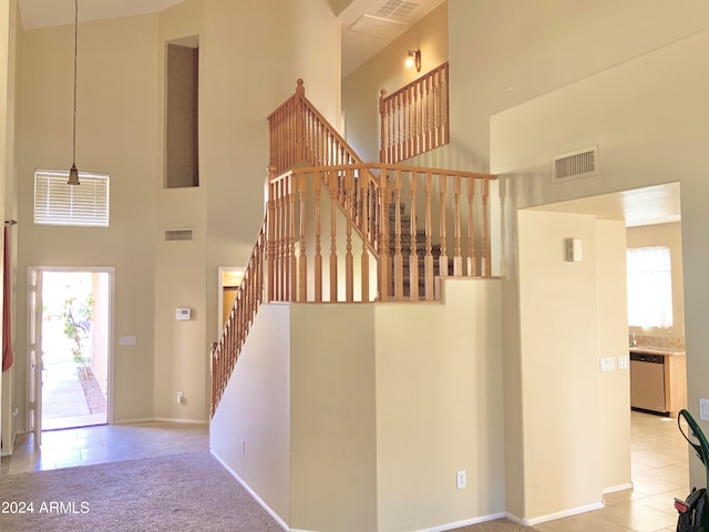 stairway with a towering ceiling, carpet flooring, and a wealth of natural light