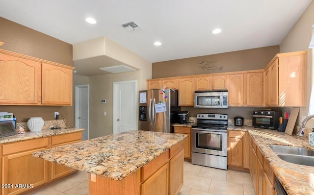 kitchen featuring a kitchen island, light stone counters, stainless steel appliances, sink, and light tile patterned floors