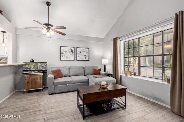 living area with light wood-style floors, ceiling fan, baseboards, and vaulted ceiling