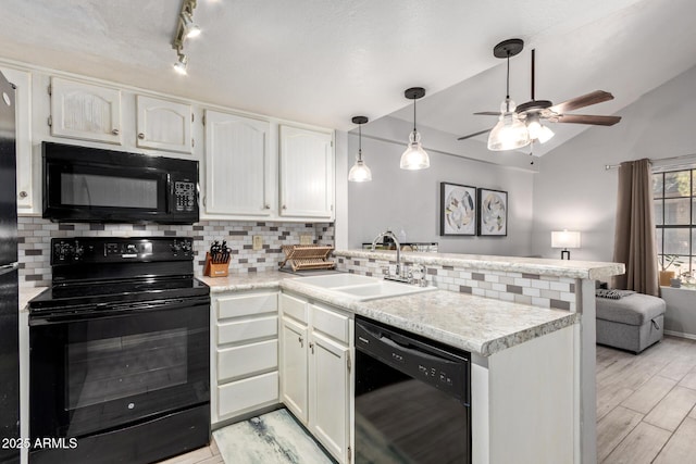 kitchen featuring white cabinets, lofted ceiling, a peninsula, black appliances, and a sink