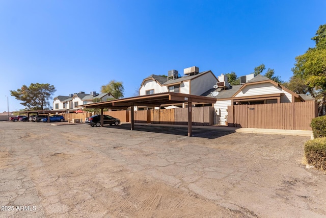 view of home's exterior with central air condition unit, covered parking, and fence