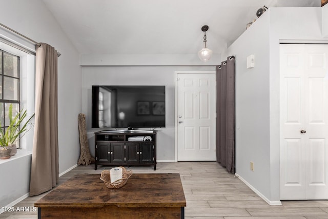 living room with lofted ceiling, baseboards, and light wood finished floors